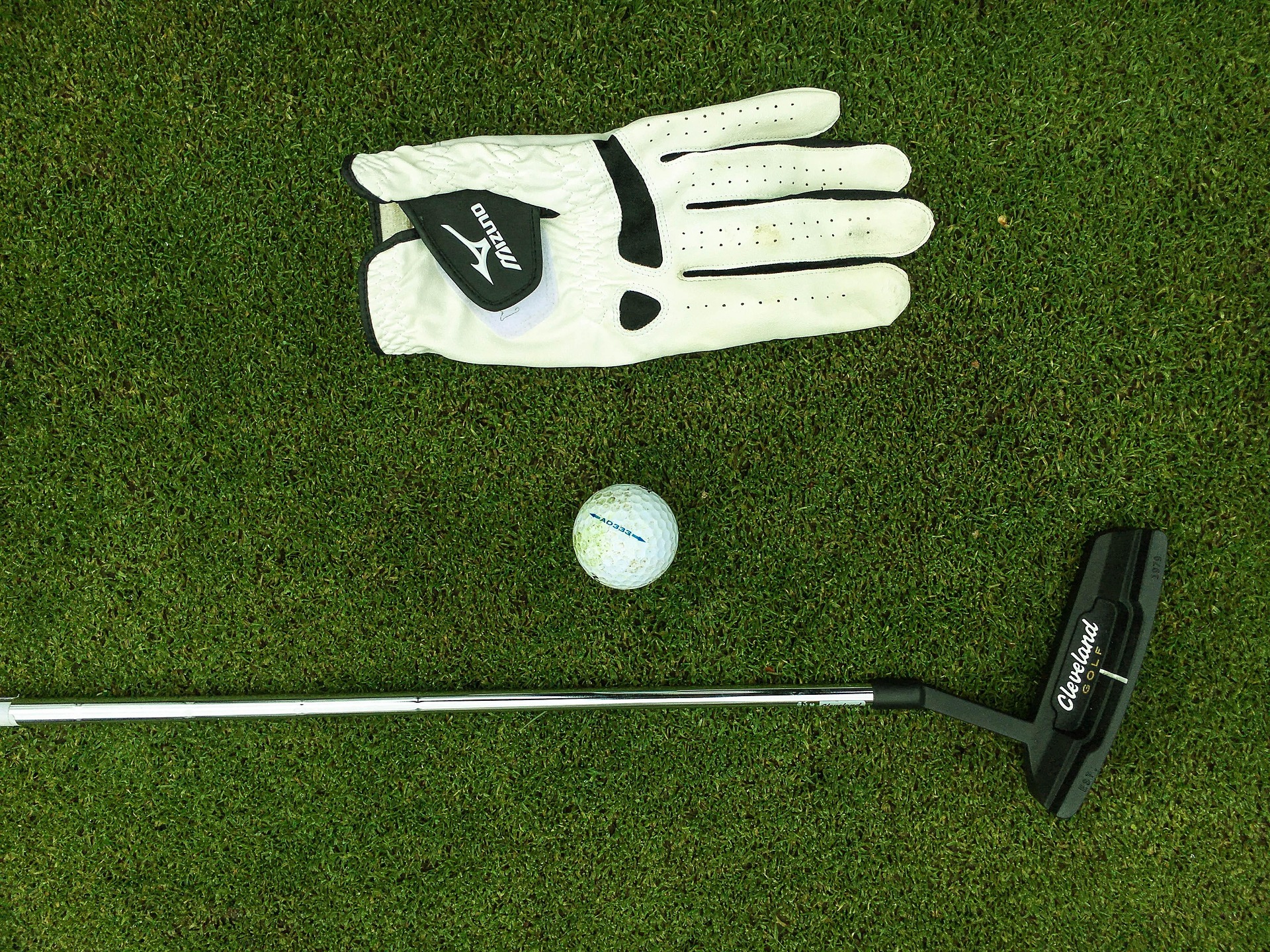 Golf House putter, glove and ball laid out on the green